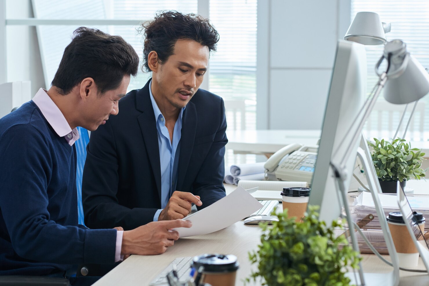 two asian businessmen sitting desk together discussing document_1098 20418